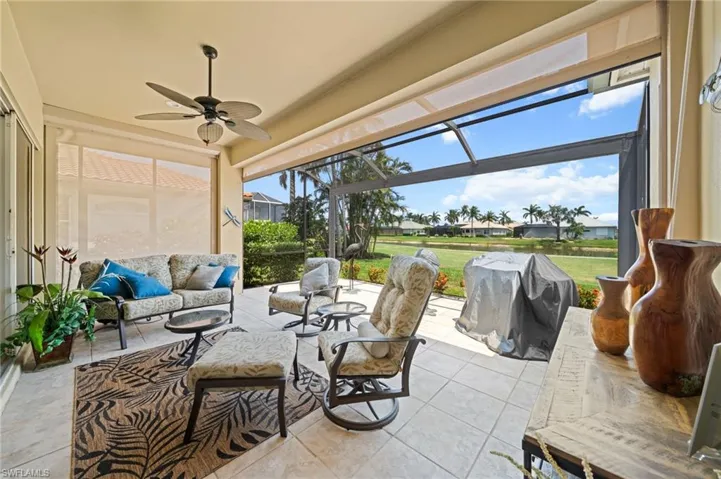 View of patio with an outdoor hangout area, a ceiling fan, glass enclosure, and area for grilling
