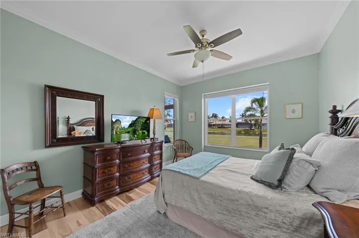 Bedroom featuring wood finished floors, crown molding, baseboards, and a ceiling fan