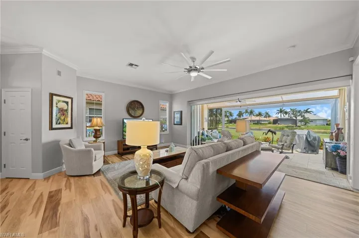 Living area featuring ceiling fan, crown molding, light wood finished floors, and baseboards