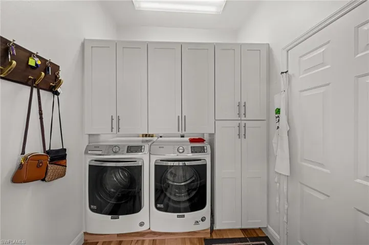 Washroom with cabinet space, independent washer and dryer, and wood finished floors