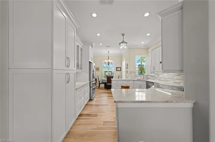 Kitchen with stainless steel appliances, crown molding, a sink, a peninsula, and light wood-type flooring