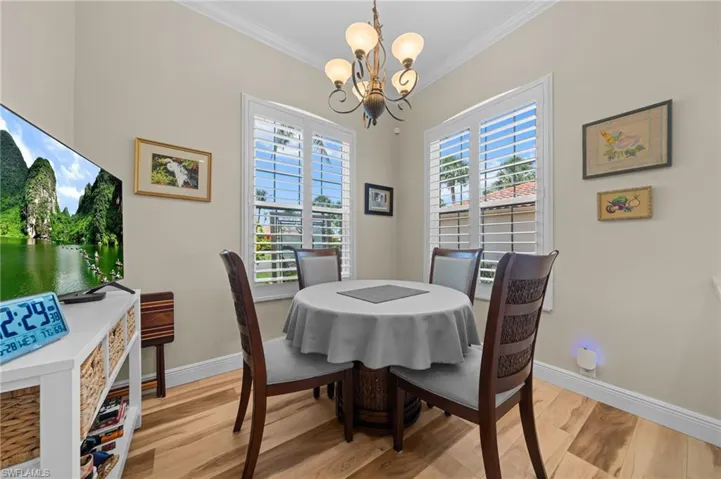 Dining area with a chandelier, ornamental molding, light wood-style floors, and baseboards
