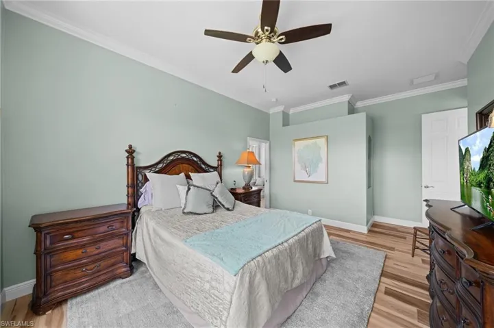 Bedroom featuring baseboards, wood finished floors, crown molding, and a ceiling fan