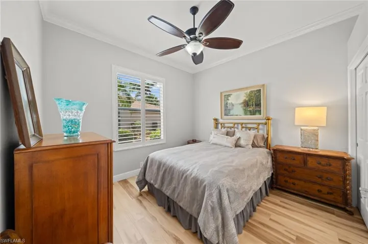 Bedroom featuring light wood finished floors, crown molding, a ceiling fan, and baseboards