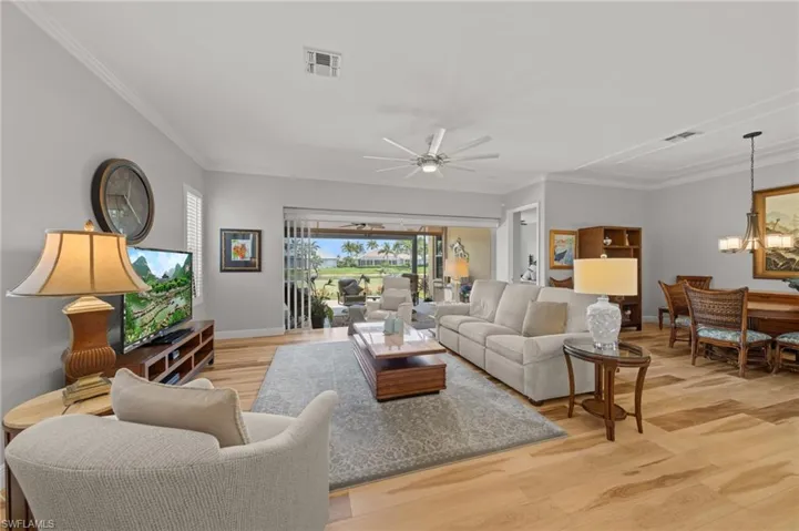 Living area featuring a chandelier, light wood-style floors, crown molding, a ceiling fan, and baseboards