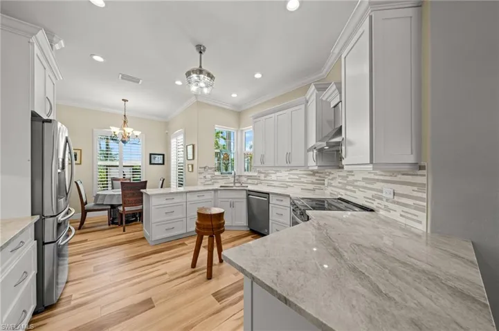 Kitchen featuring stainless steel appliances, a chandelier, a sink, light wood-type flooring, and backsplash