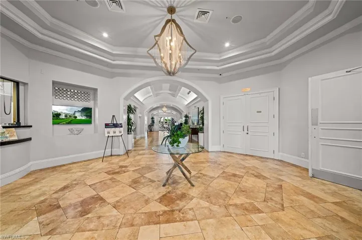 Foyer entrance with arched walkways, crown molding, a tray ceiling, a chandelier, and recessed lighting