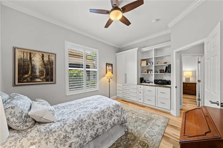 Bedroom with ornamental molding, light wood-style floors, and a ceiling fan