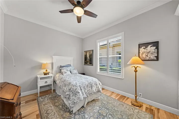Bedroom with crown molding, baseboards, light wood-type flooring, and a ceiling fan