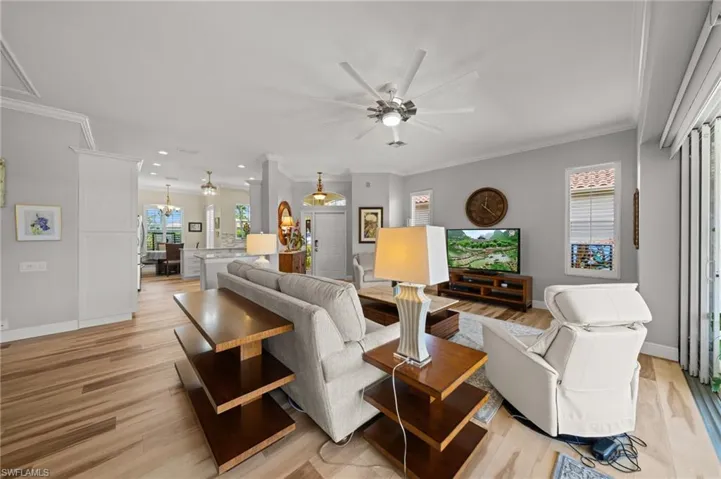 Living room featuring a ceiling fan, ornamental molding, light wood finished floors, baseboards, and recessed lighting