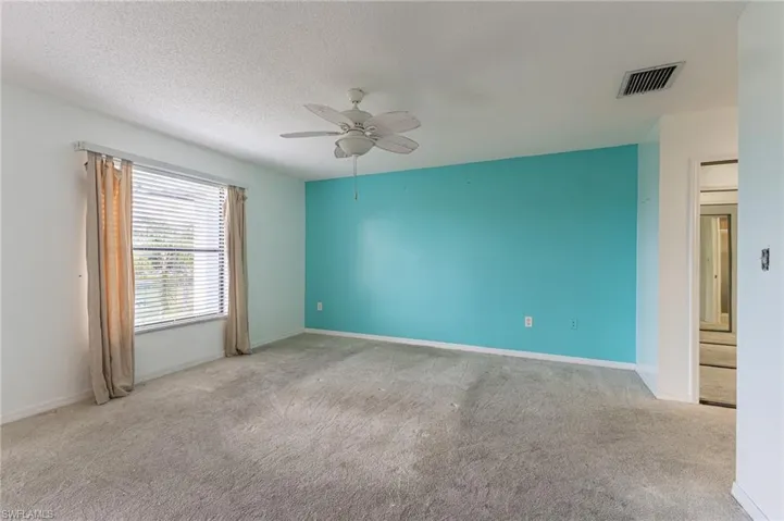 Unfurnished room with light colored carpet, ceiling fan, and a textured ceiling