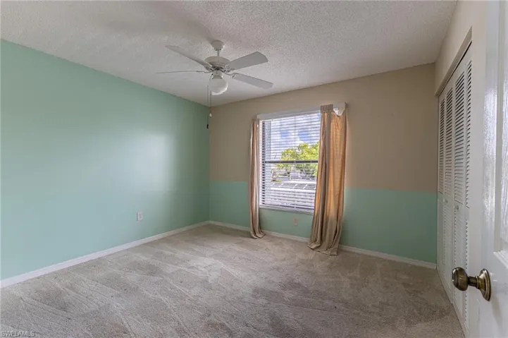 Unfurnished bedroom featuring a textured ceiling, ceiling fan, carpet flooring, and a closet