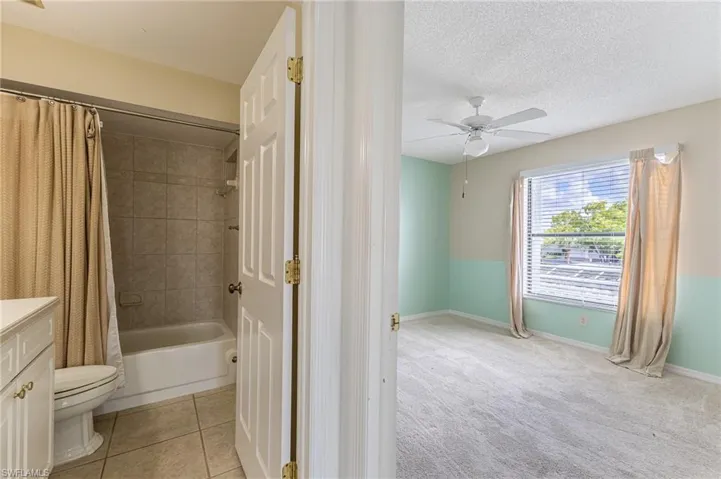 Full bathroom featuring vanity, shower / tub combo with curtain, light carpet, light tile patterned floors, and a textured ceiling