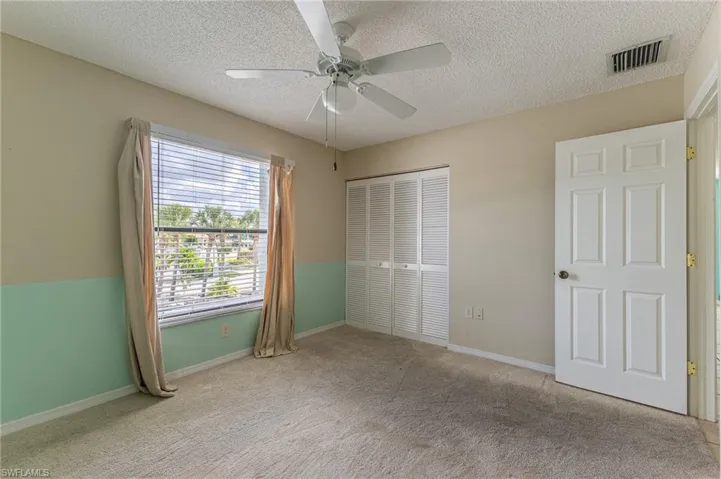 Unfurnished bedroom with a textured ceiling, light carpet, a closet, and ceiling fan