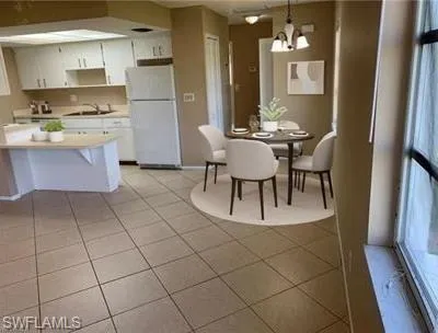 Kitchen featuring light countertops, white cabinets, freestanding refrigerator, and a chandelier