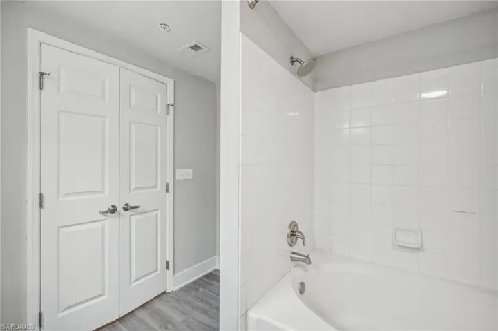 Bathroom with hardwood / wood-style floors and tiled shower / bath combo