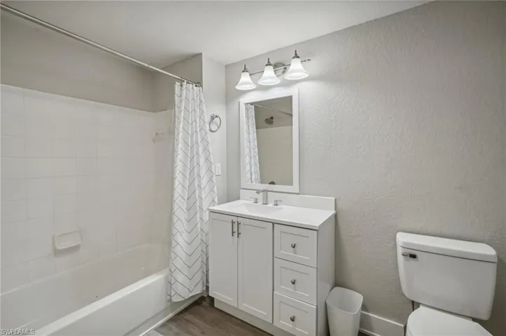 Full bathroom with shower / bath combo, hardwood / wood-style floors, toilet, and vanity