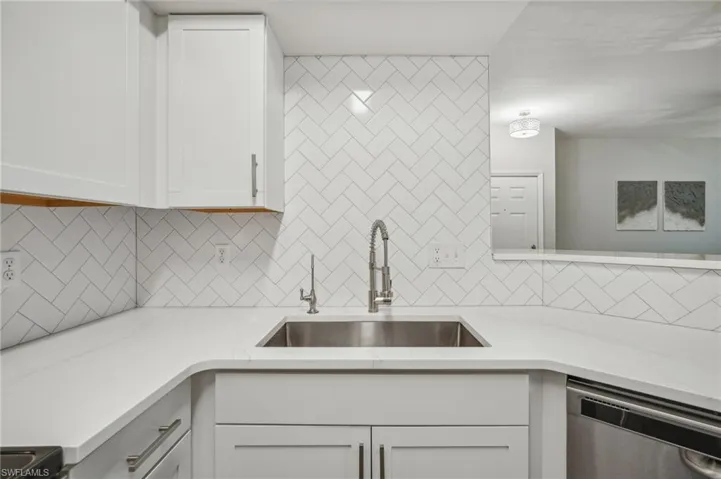 Kitchen featuring sink, dishwasher, tasteful backsplash, and white cabinetry
