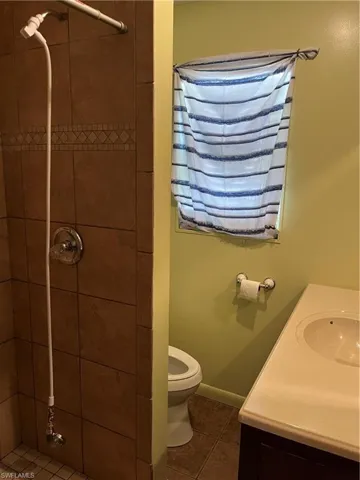 Bathroom featuring toilet, vanity, tile patterned flooring, and a tile shower