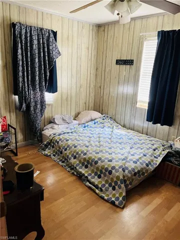 Bedroom with ceiling fan, hardwood / wood-style flooring, and wooden walls
