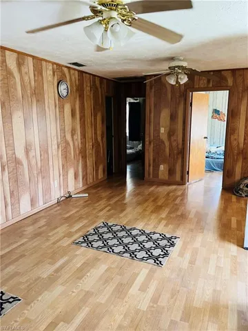 Empty room featuring hardwood / wood-style floors, wood walls, and a textured ceiling