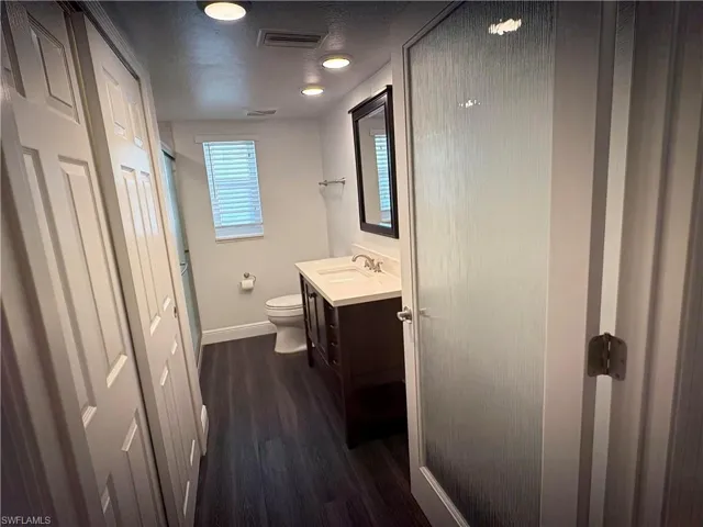 Full bath featuring vanity, dark wood-style flooring, a shower with shower door, and a textured ceiling