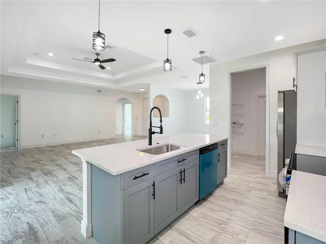 Kitchen featuring sink, dishwasher, a center island with sink, and pendant lighting