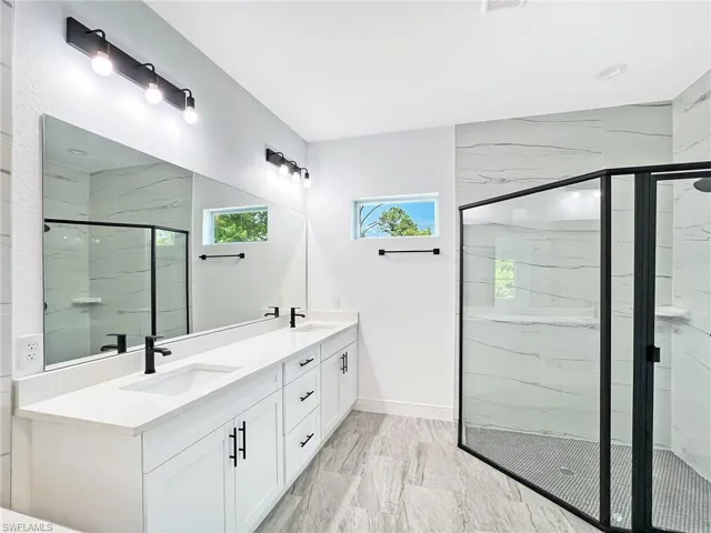 Bathroom with dual bowl vanity and a shower with door