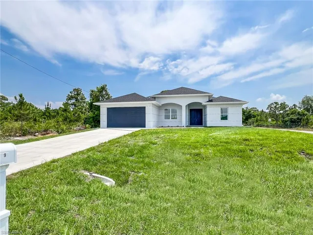 View of front of property with a garage and a front lawn