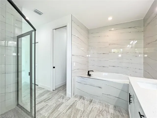 Bathroom featuring shower with separate bathtub and vanity