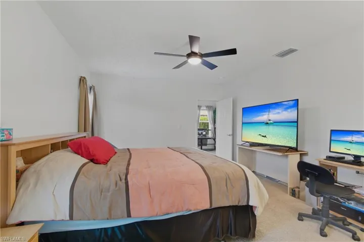 Carpeted bedroom with an office area and ceiling fan