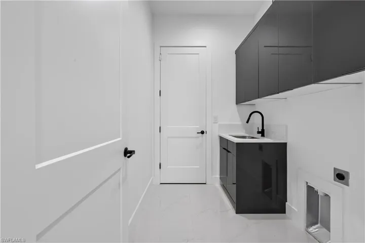Laundry area with cabinet space, marble finish floor, hookup for an electric dryer, and a sink