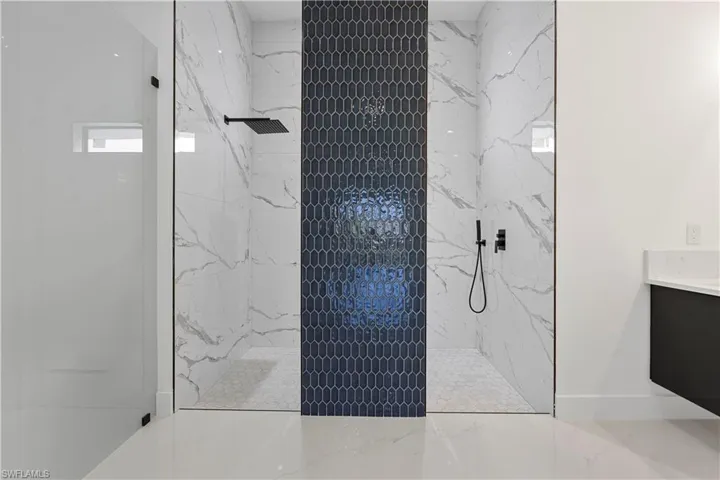Full bath featuring a marble finish shower, baseboards, and vanity