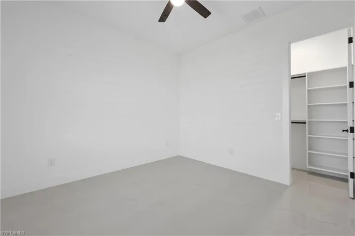 Unfurnished bedroom with a closet, visible vents, a walk in closet, and baseboards