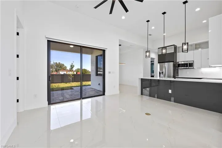 Kitchen featuring marble finish floor, modern cabinets, stainless steel appliances, light countertops, and hanging light fixtures