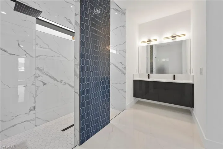 Full bath featuring baseboards, a marble finish shower, double vanity, a sink, and marble finish floor
