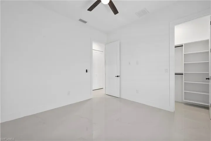 Unfurnished bedroom featuring a spacious closet, baseboards, visible vents, and marble finish floor