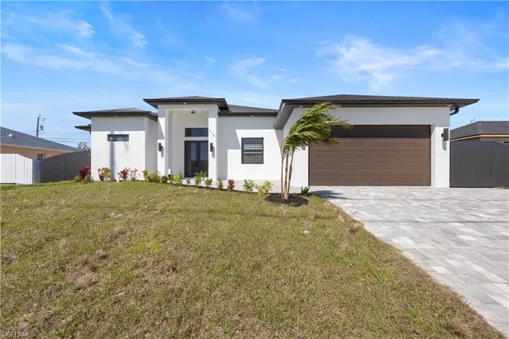 Prairie-style house with stucco siding, decorative driveway, an attached garage, and fence