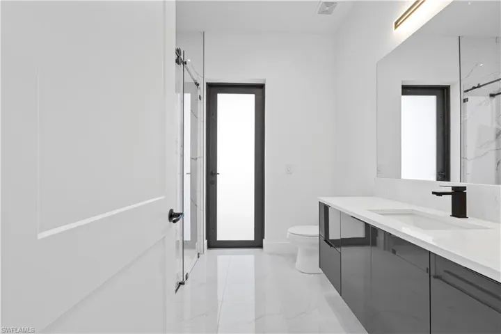 Full bath featuring visible vents, baseboards, toilet, marble finish floor, and vanity