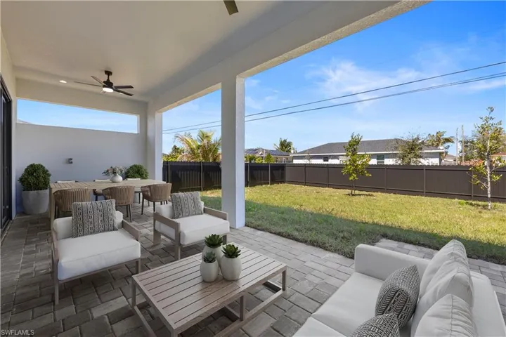 Virtually Staged-View of patio featuring a fenced backyard, an outdoor hangout area, and a ceiling fan