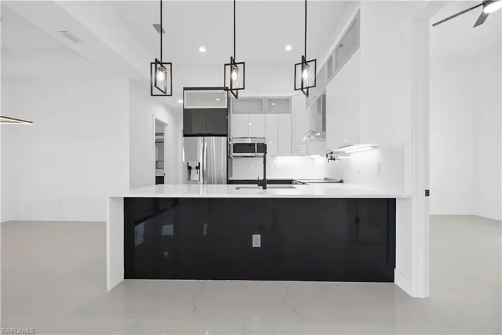 Kitchen with visible vents, appliances with stainless steel finishes, a peninsula, white cabinetry, and modern cabinets