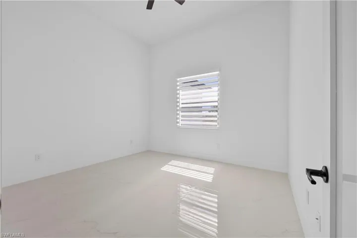 Unfurnished room featuring marble finish floor, baseboards, and ceiling fan