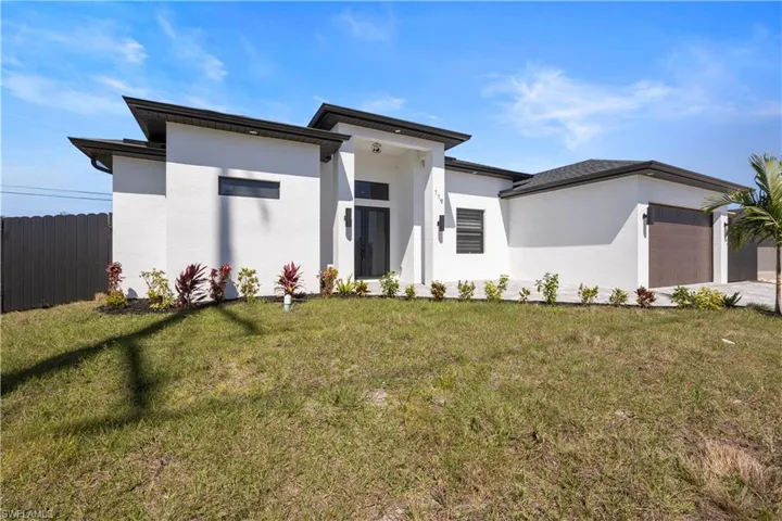 Prairie-style home with a front yard, an attached garage, fence, and stucco siding
