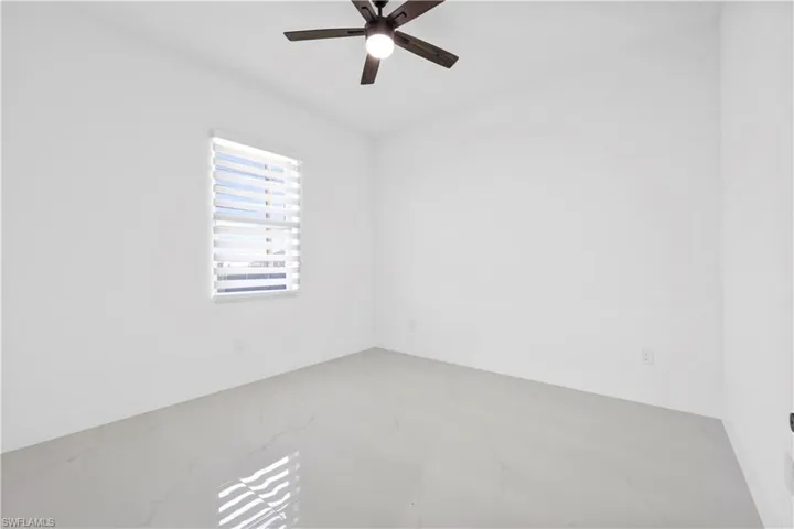 Empty room with baseboards, marble finish floor, and ceiling fan