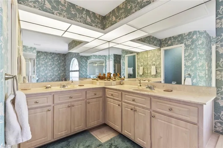 Full bath with wallpapered walls, double vanity, and tile patterned floors