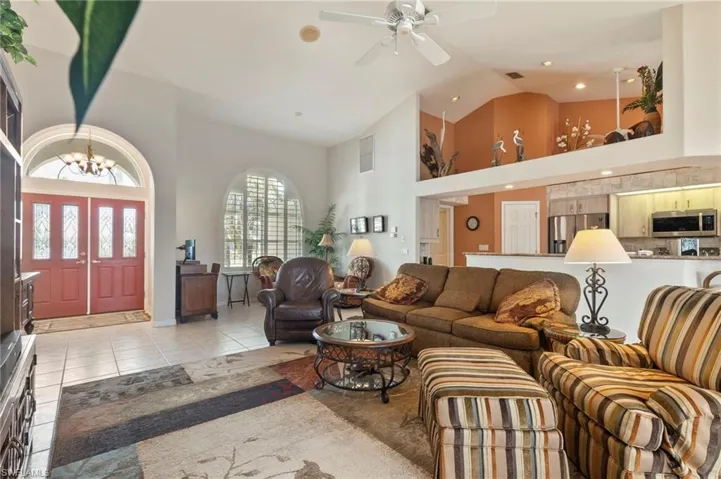 Living room featuring high vaulted ceiling, a ceiling fan, light tile patterned floors, and a chandelier