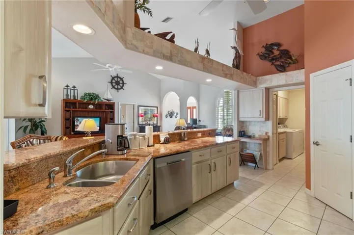 Kitchen with a ceiling fan, stainless steel dishwasher, light tile patterned floors, light stone counters, and recessed lighting