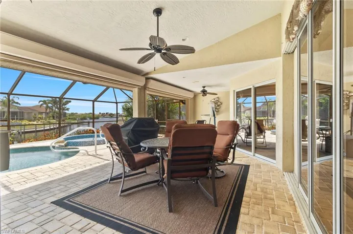 Sunroom featuring vaulted ceiling, a pool, a ceiling fan, outdoor dining area, and a water view