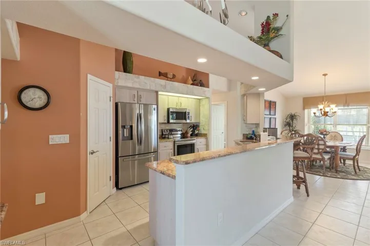 Kitchen featuring stainless steel appliances, light tile patterned flooring, a chandelier, a peninsula, and recessed lighting