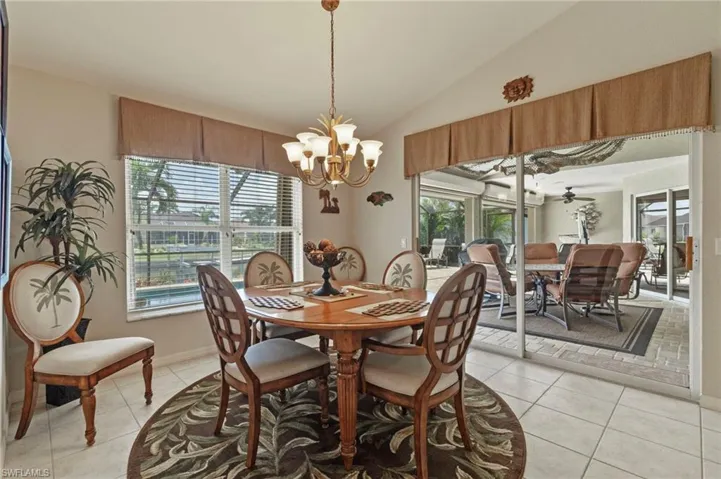Dining space with vaulted ceiling, light tile patterned flooring, a chandelier, and plenty of natural light